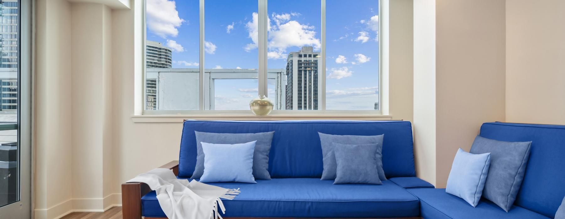 a room with blue couches and a large window with a city skyline