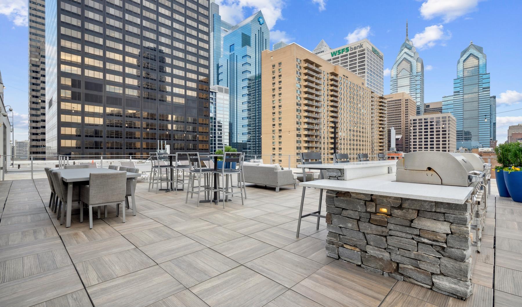 A perfect fit for the whole family a patio with tables and chairs in front of a city